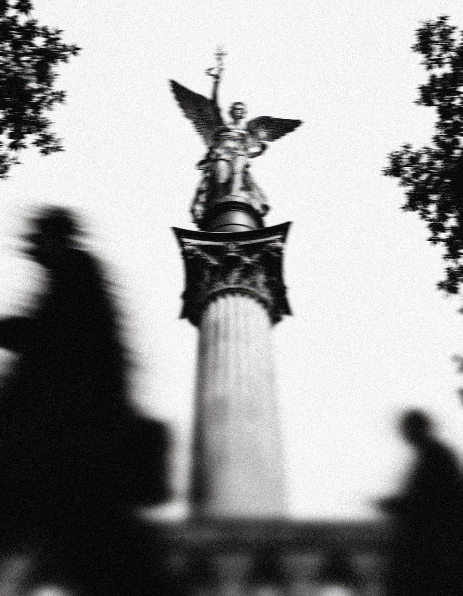 The Angel of Peace column in Munich, with passers-by blurred in motion