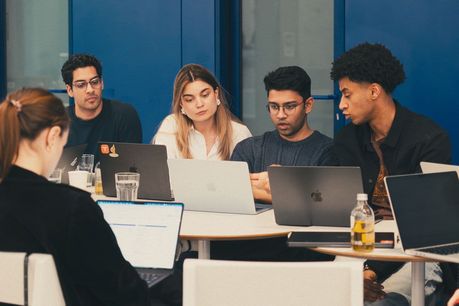 Colleagues working on laptops around a round table