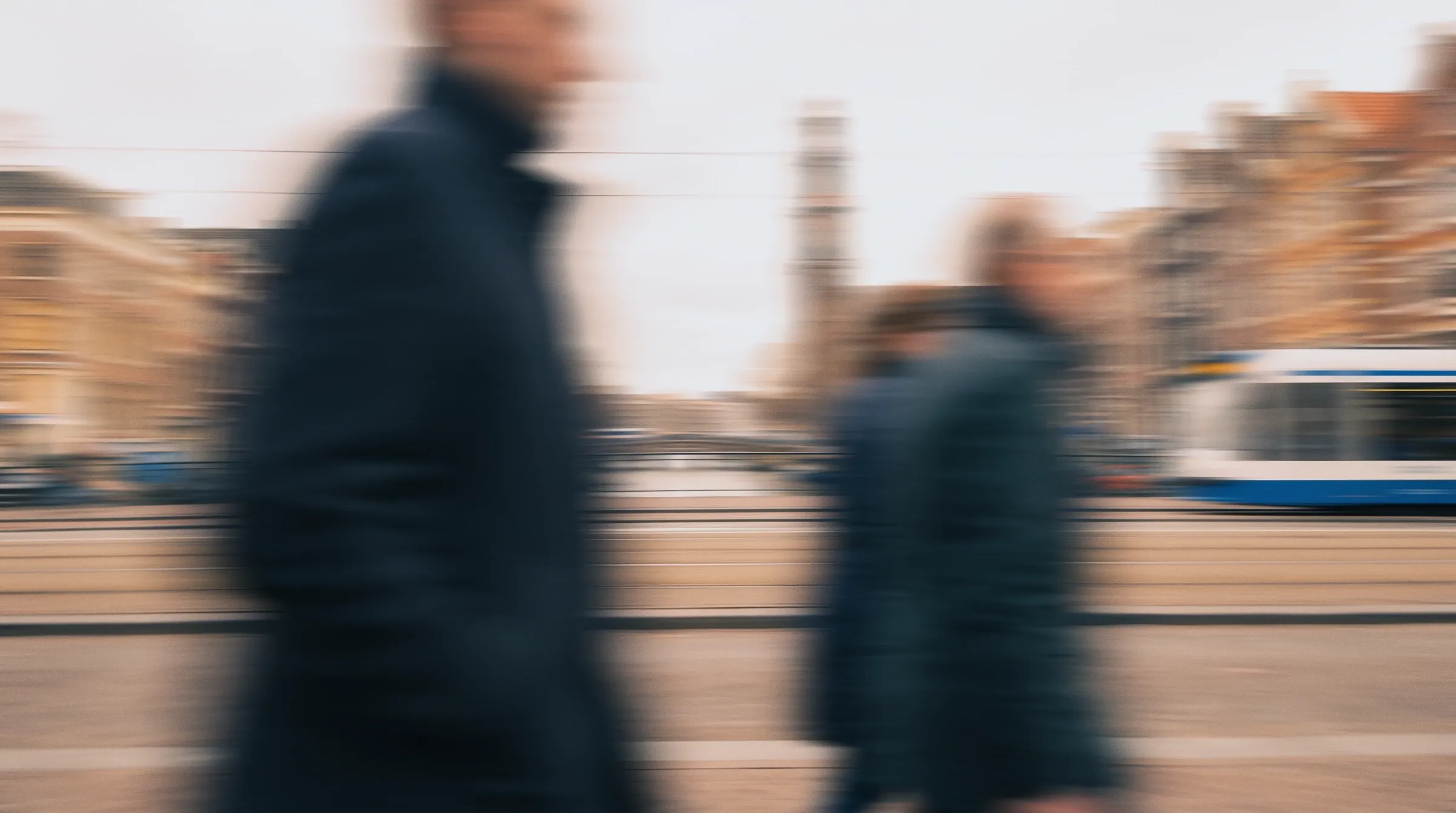 People walking past a tram in Amsterdam, blurred in motion