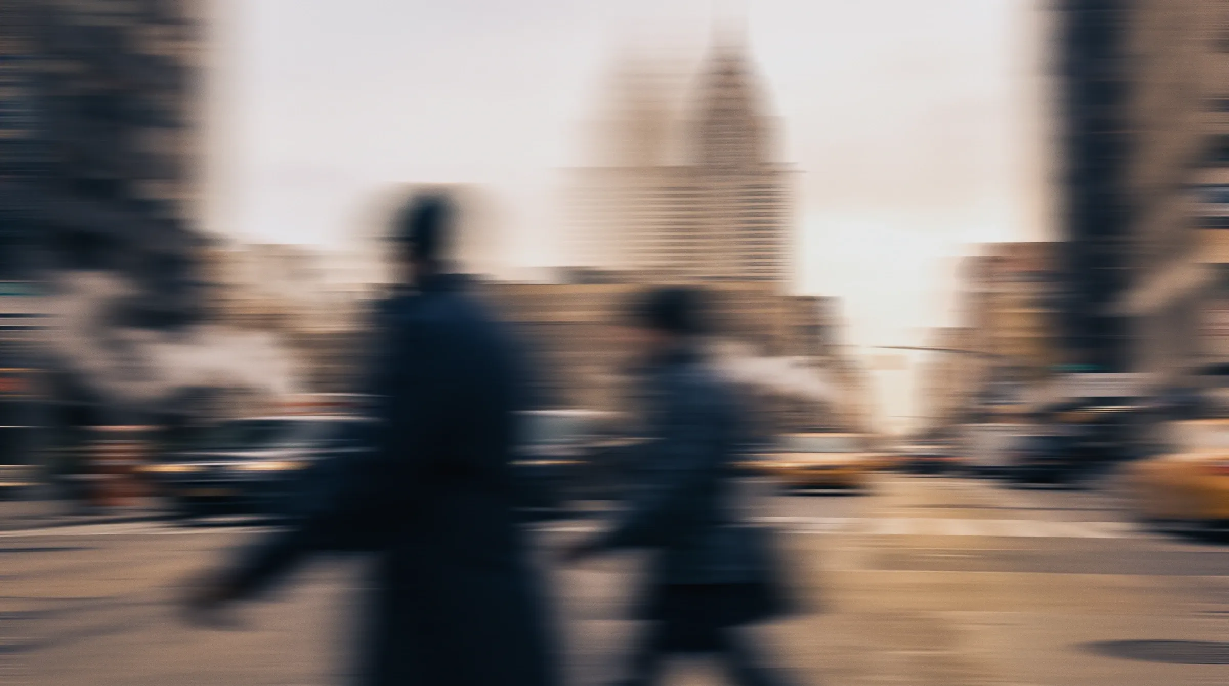Commuters crossing a Midtown New York street, blurred in motion